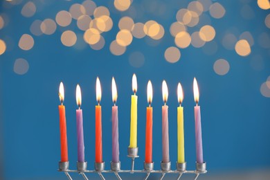 Hanukkah celebration. Menorah with burning candles on blue background with blurred lights