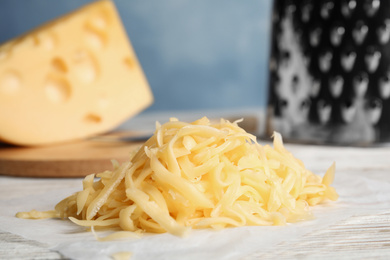 Photo of Tasty grated cheese on white wooden table, closeup