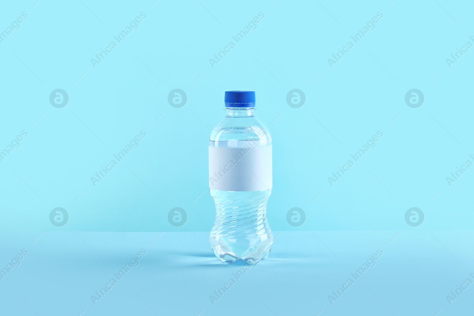 Photo of Plastic bottle of pure water with blank tag on color background