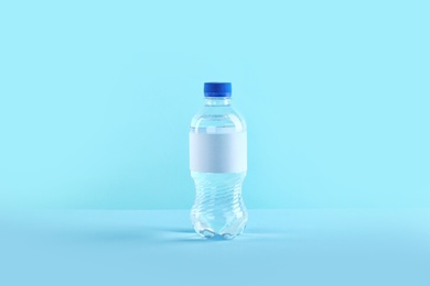 Plastic bottle of pure water with blank tag on color background