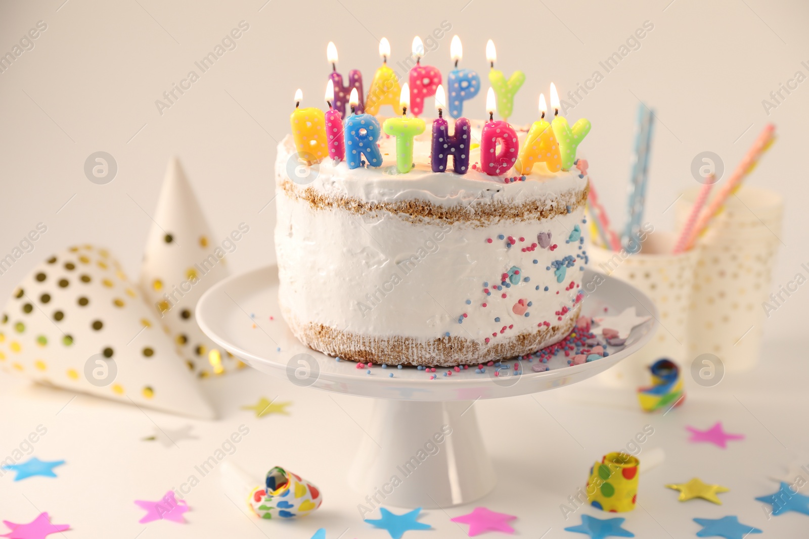 Photo of Tasty Birthday cake with burning candles and party decor on white table