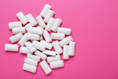 Photo of Tasty white chewing gums on pink background, flat lay. Space for text