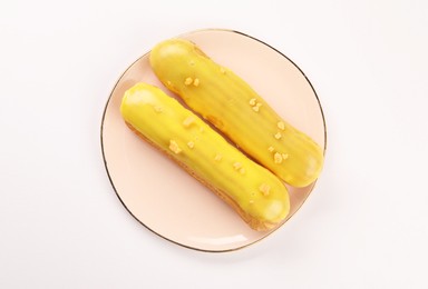 Delicious eclairs covered with glaze on white background, top view