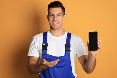 Photo of Repairman with modern smartphone on orange background