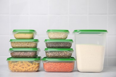 Plastic containers filled with food products on white table near tiled wall