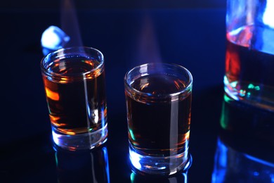 Photo of Flaming alcohol drink in shot glasses on mirror surface