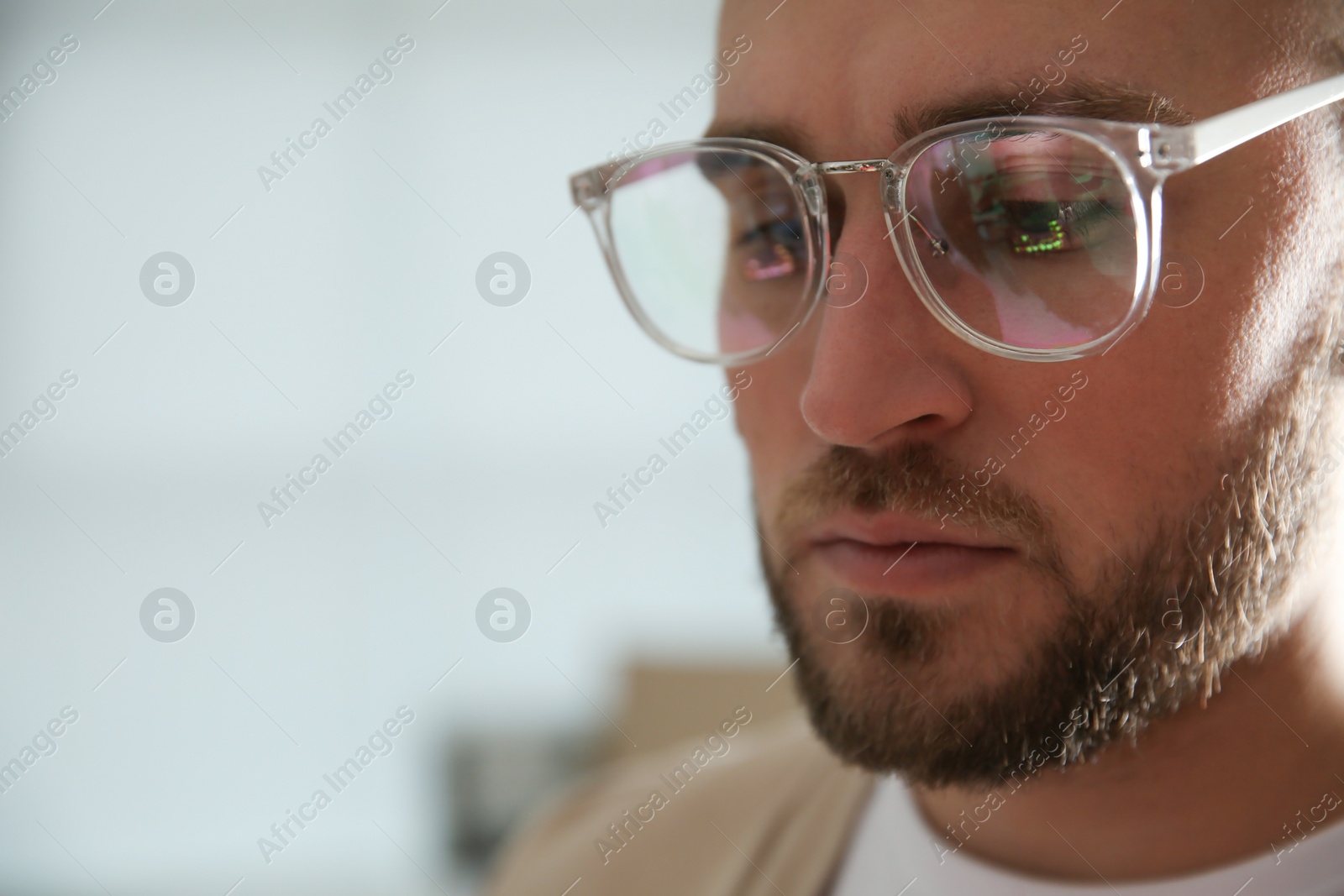 Photo of Young man wearing glasses on blurred background, closeup. Ophthalmology service