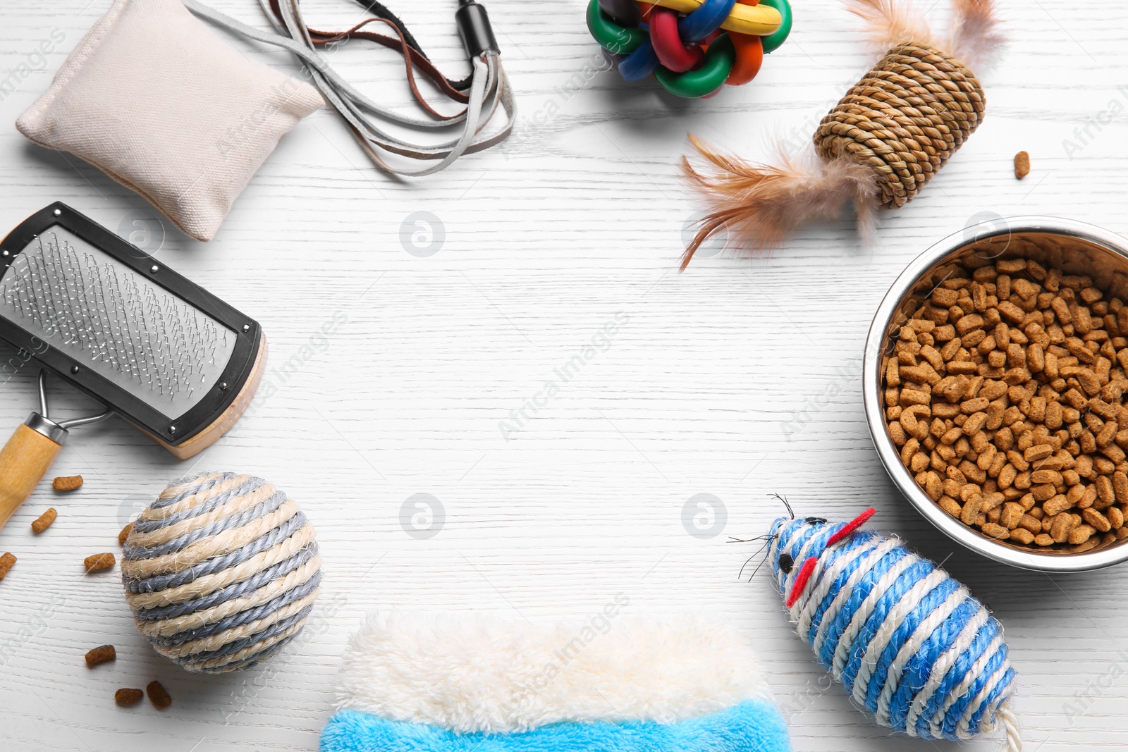 Photo of Flat lay composition with cat toys, food and accessories on white wooden table. Space for text