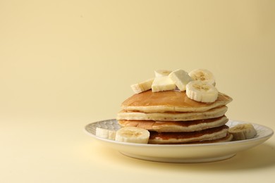 Photo of Delicious pancakes with bananas, honey and butter on beige background. Space for text