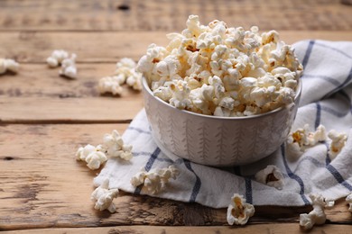 Photo of Bowl of tasty popcorn on wooden table, space for text