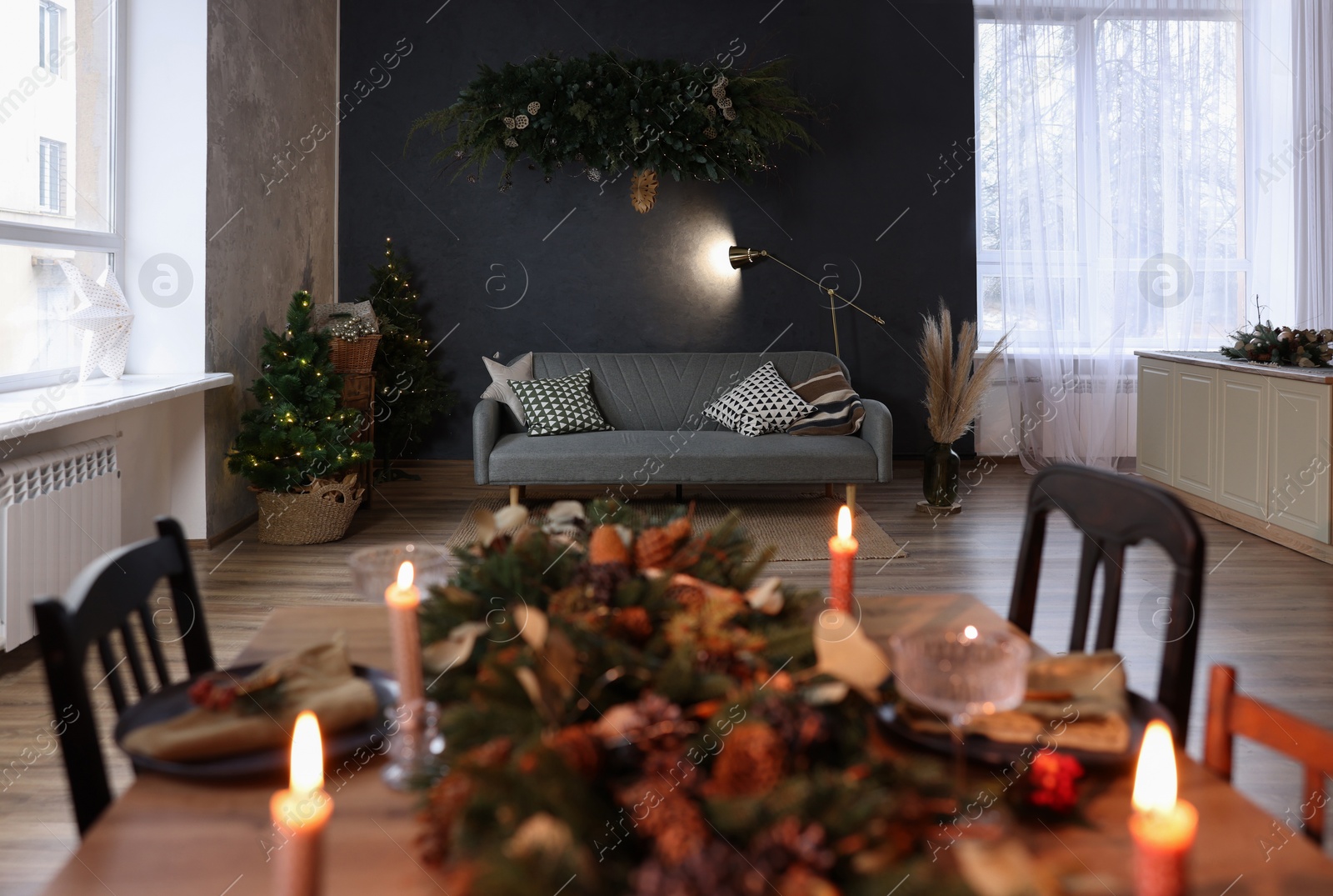 Photo of Dining table with burning candles and Christmas decor in stylish room. Interior design