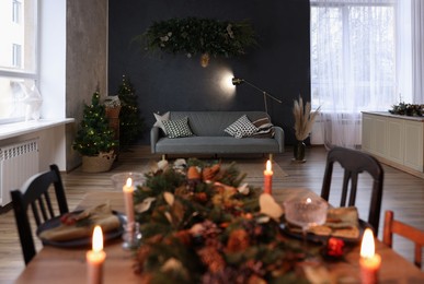 Photo of Dining table with burning candles and Christmas decor in stylish room. Interior design