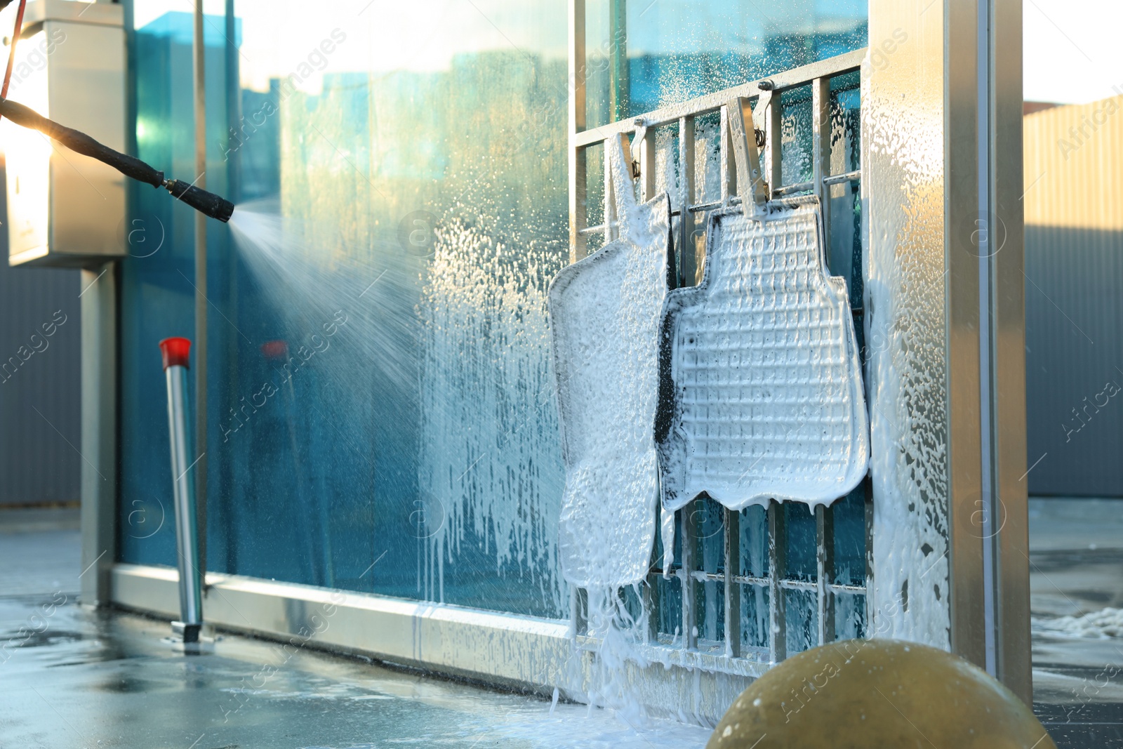 Photo of Cleaning auto mats with high pressure foam jet at car wash, closeup