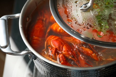 Photo of Fresh delicious crayfishes in boiling water, closeup