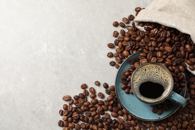 Cup of aromatic hot coffee and beans on light grey table, flat lay. Space for text