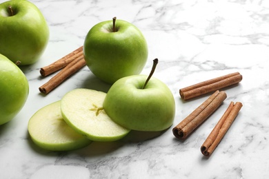 Photo of Fresh apples and cinnamon sticks on marble table