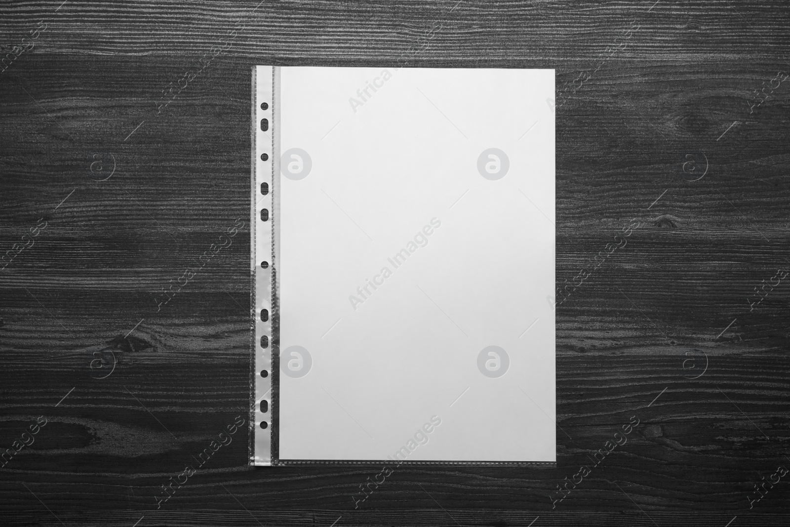 Photo of Punched pocket with paper sheet on black wooden table, top view