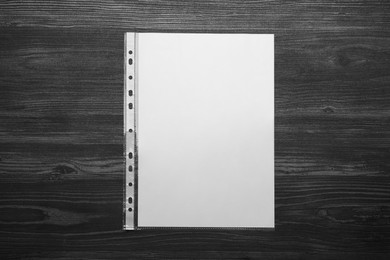 Photo of Punched pocket with paper sheet on black wooden table, top view