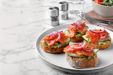 Photo of Delicious sandwiches with salmon, avocado, cucumber and onion on white marble table. Space for text