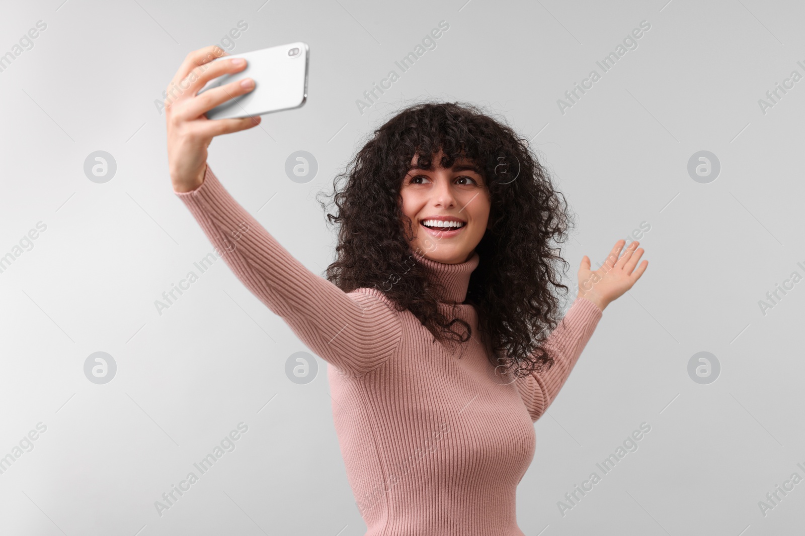 Photo of Beautiful young woman taking selfie on light grey background