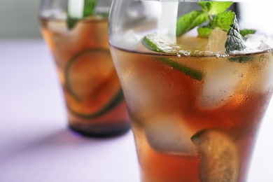 Glasses of refreshing iced tea on lilac background, closeup