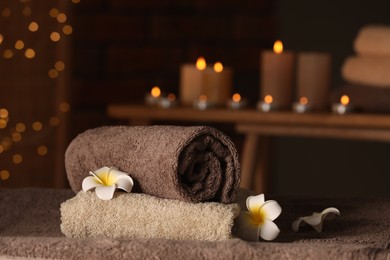 Photo of Spa composition with towels and plumeria flowers on massage table in wellness center