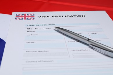 Photo of Immigration to United Kingdom. Visa application form and pen on flag, closeup