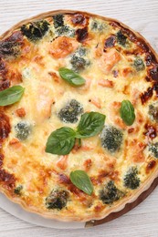 Photo of Delicious homemade quiche with salmon, broccoli and basil leaves on table, top view