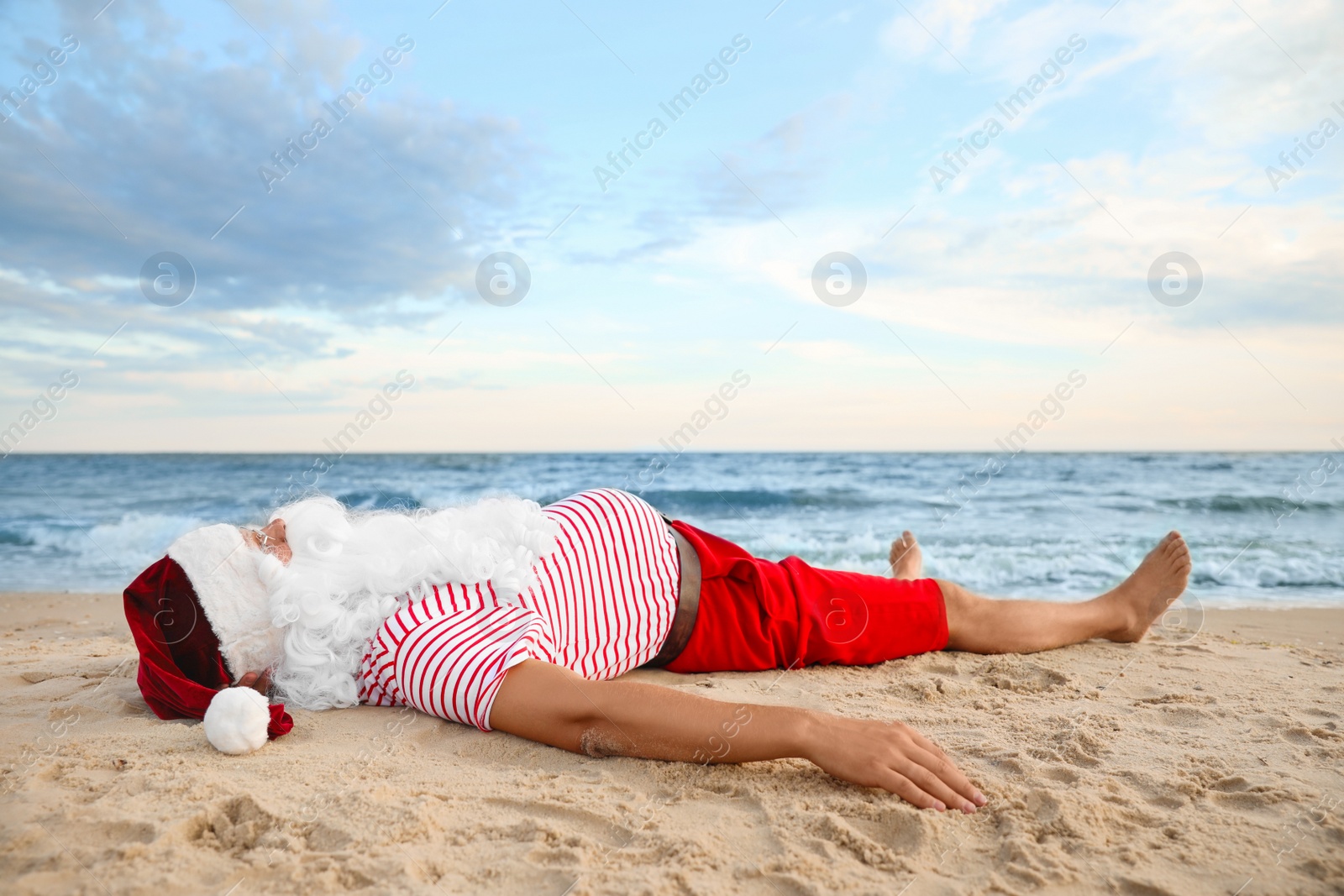 Photo of Santa Claus relaxing on beach, space for text. Christmas vacation