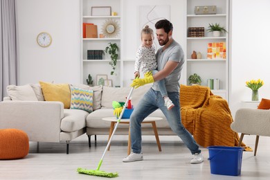 Photo of Spring cleaning. Father and daughter having fun while tidying up together at home
