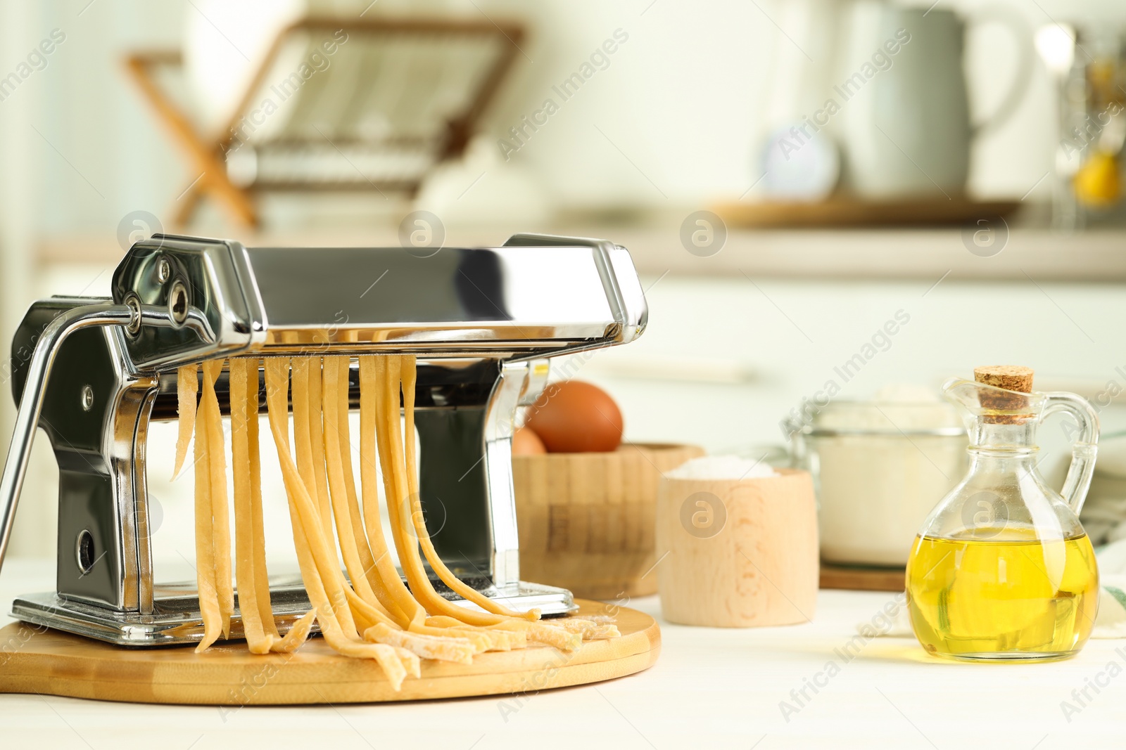 Photo of Pasta maker with raw dough and ingredients on white wooden table