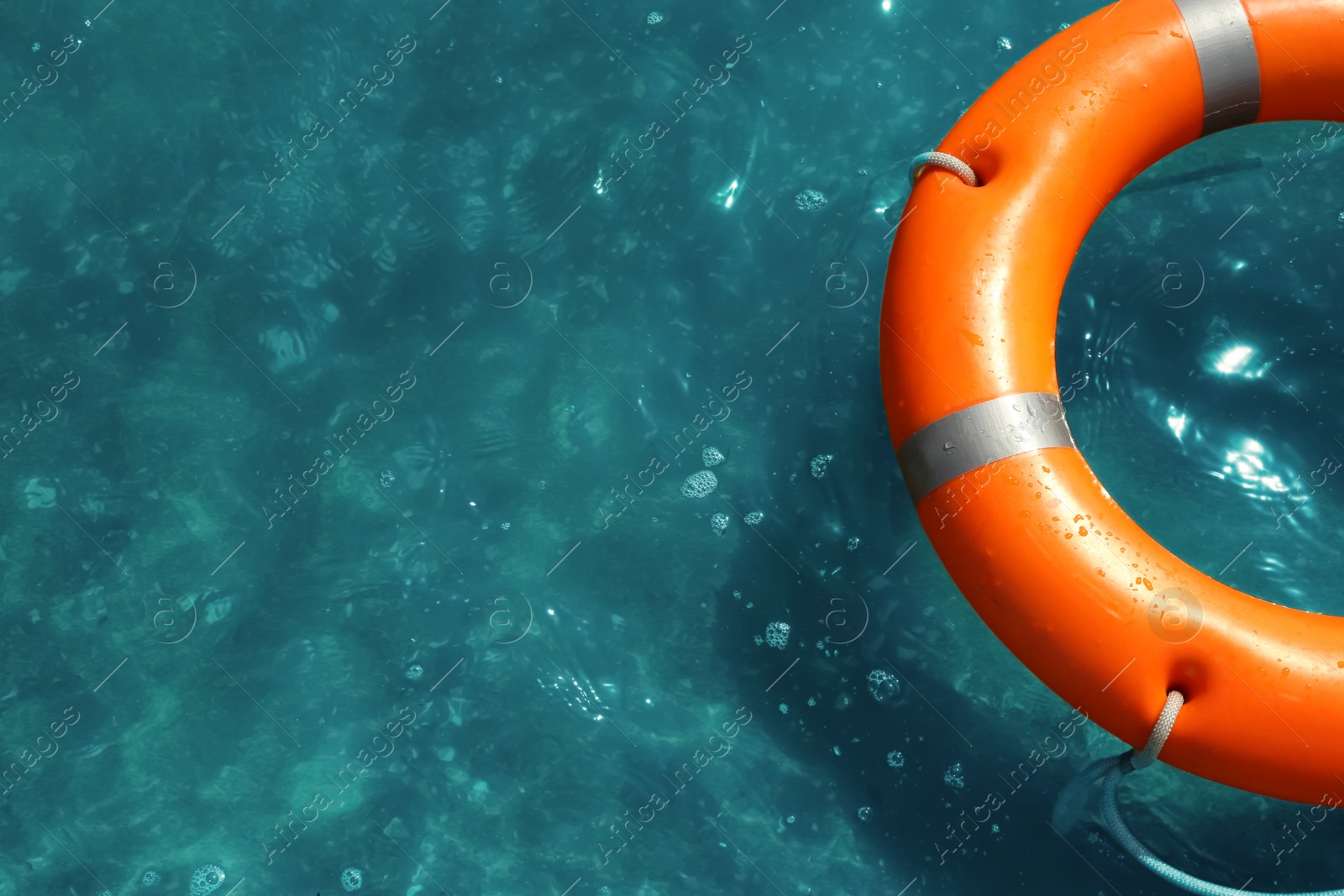 Photo of Orange life buoy floating in sea, above view. Emergency rescue equipment