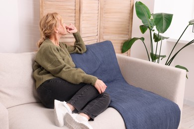 Photo of Woman sulking on sofa in living room. Loneliness concept