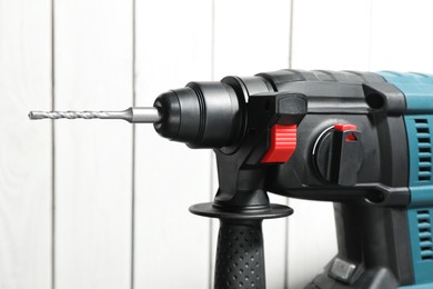 Photo of Modern electric power drill near white wooden wall, closeup