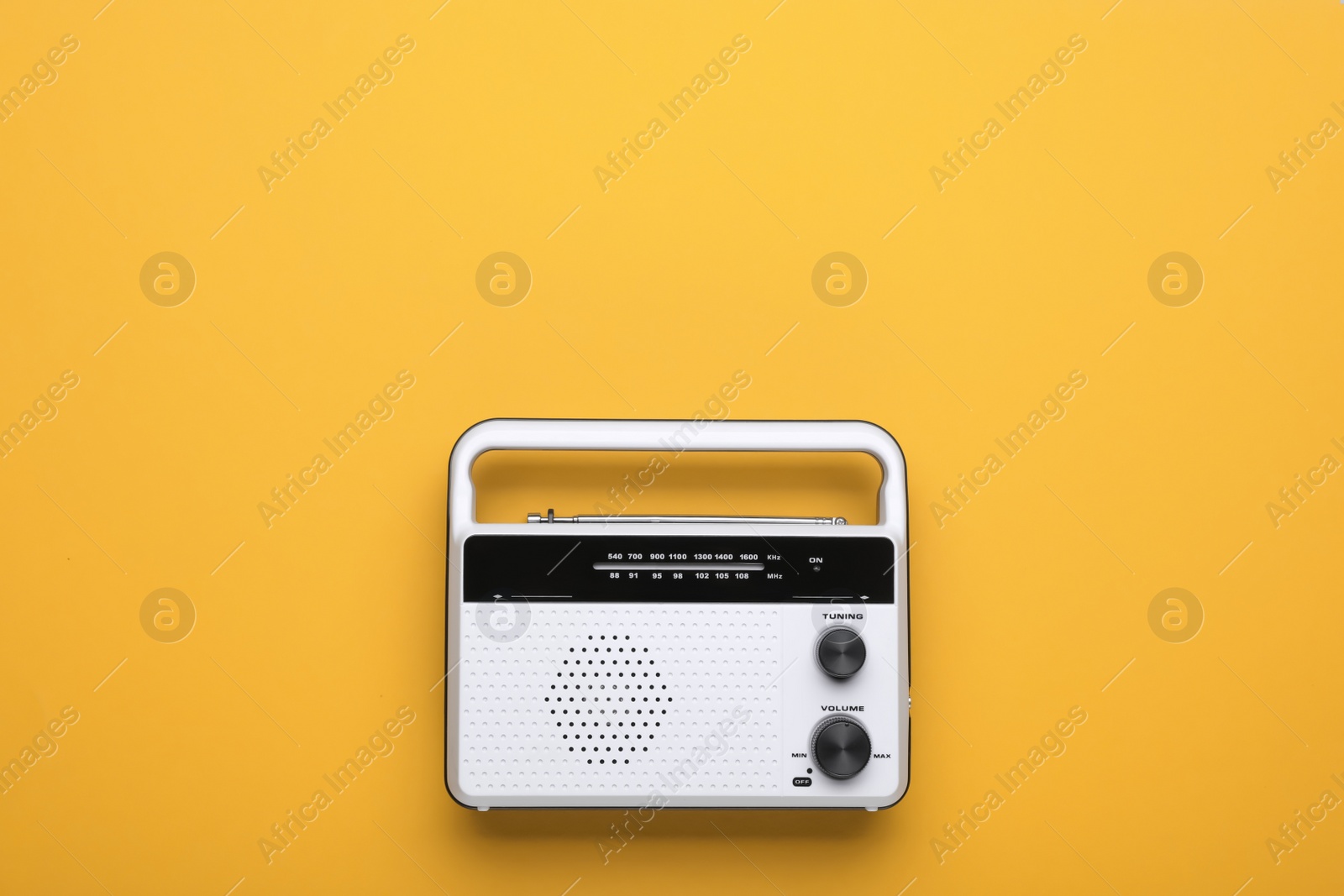 Photo of Retro radio receiver on yellow background, top view