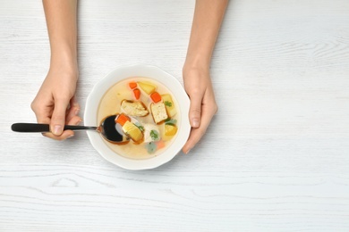 Woman eating fresh homemade chicken soup at table, top view. Space for text