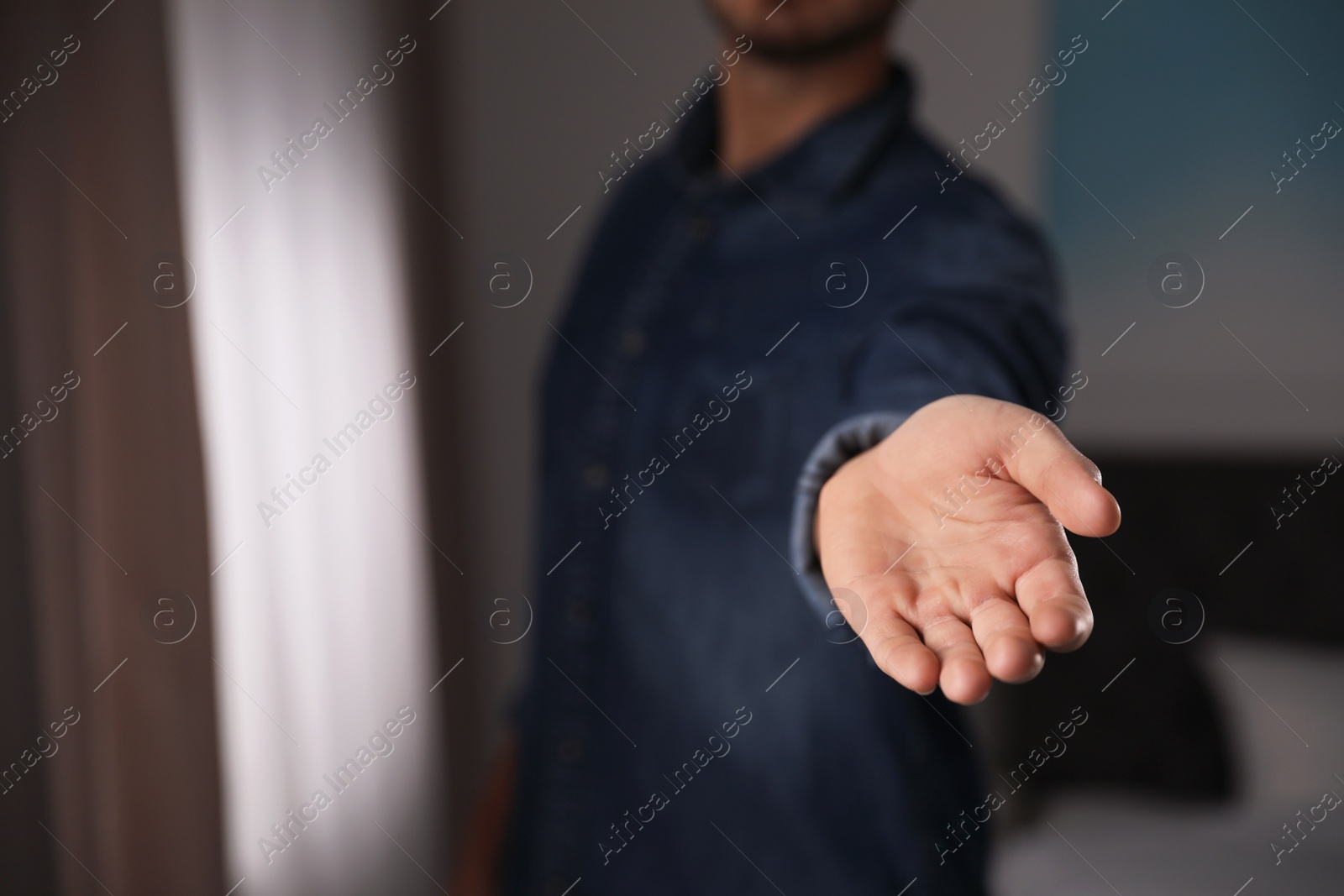 Photo of Man offering helping hand on blurred background, closeup. Space for text