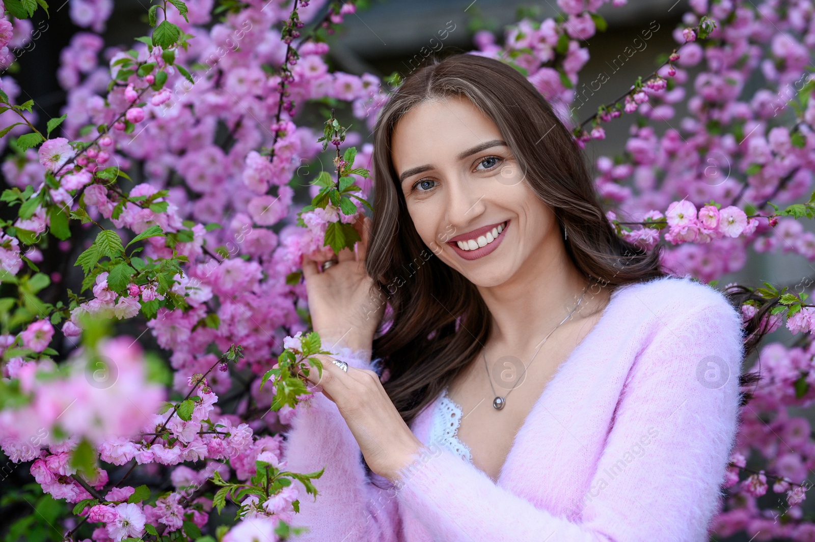 Photo of Beautiful young woman near blossoming sakura tree on spring day