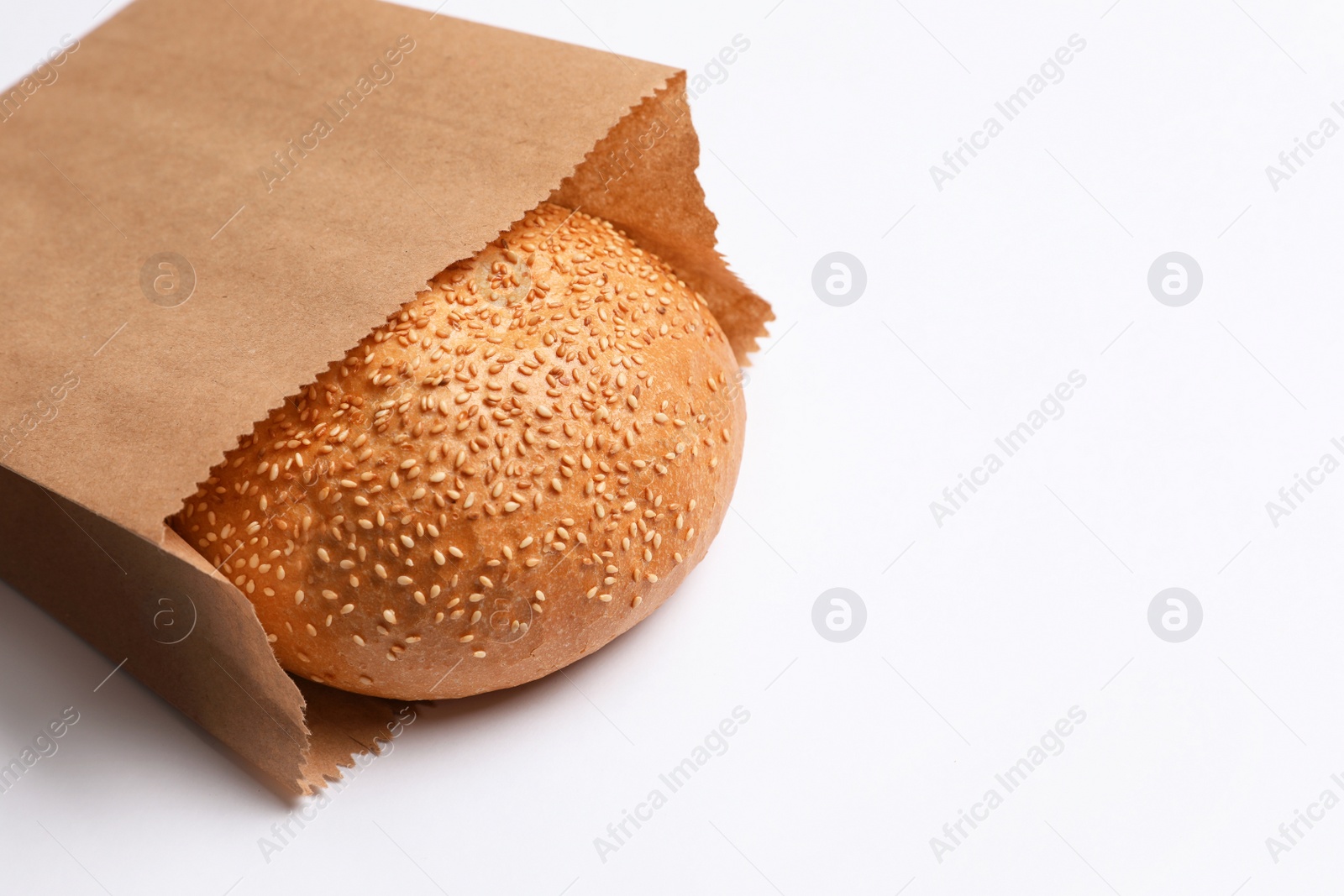 Photo of Paper bag with sesame bun on white background. Space for text