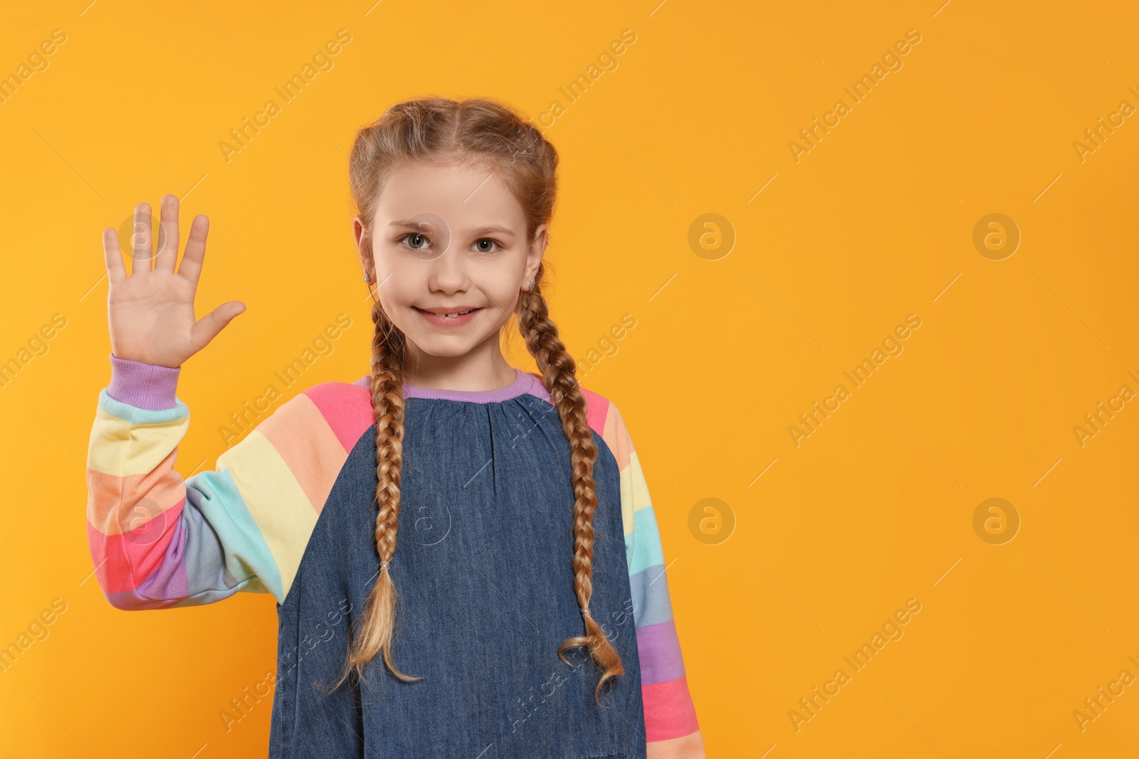 Photo of Cheerful girl giving high five on orange background, space for text