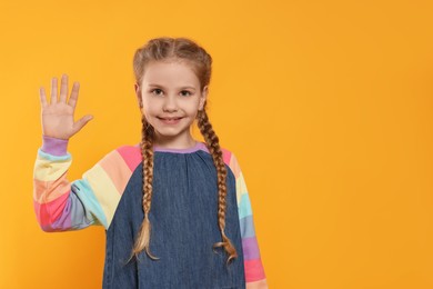 Photo of Cheerful girl giving high five on orange background, space for text