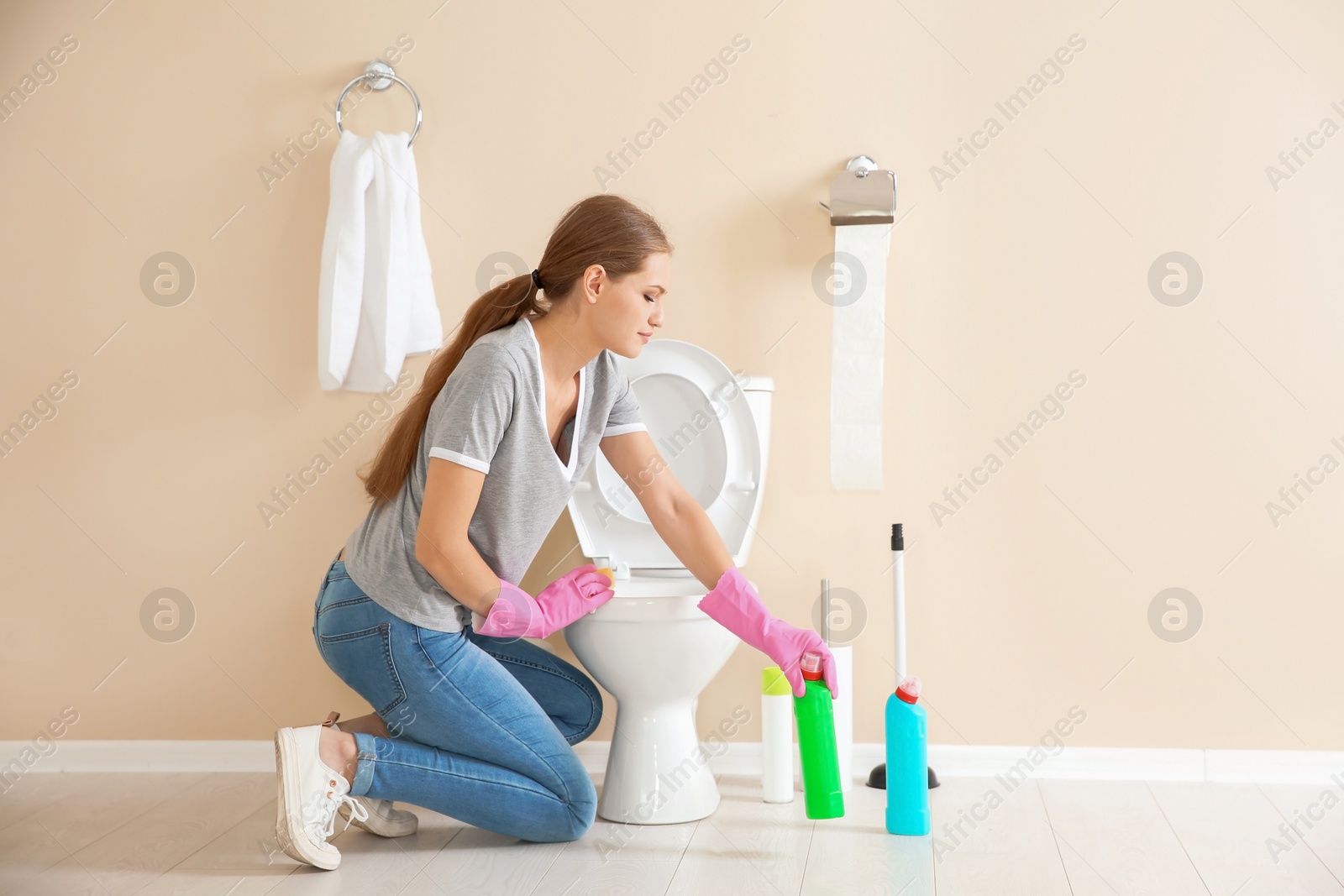 Photo of Woman cleaning toilet bowl in bathroom