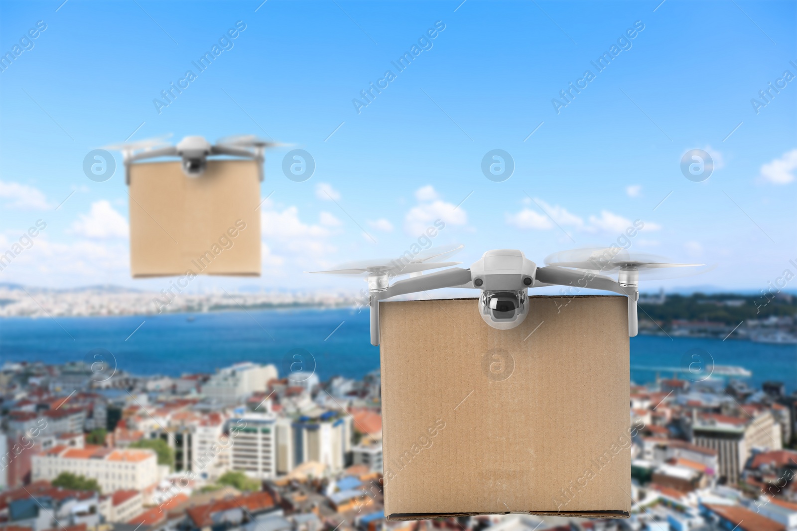 Image of Modern drones with carton boxes flying above city on sunny day. Delivery service 