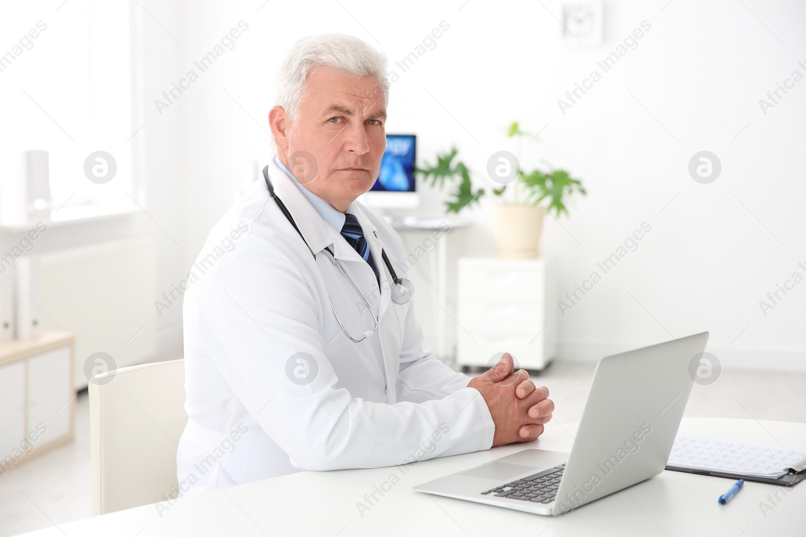 Photo of Portrait of male doctor in coat at workplace in clinic. Cardiology center