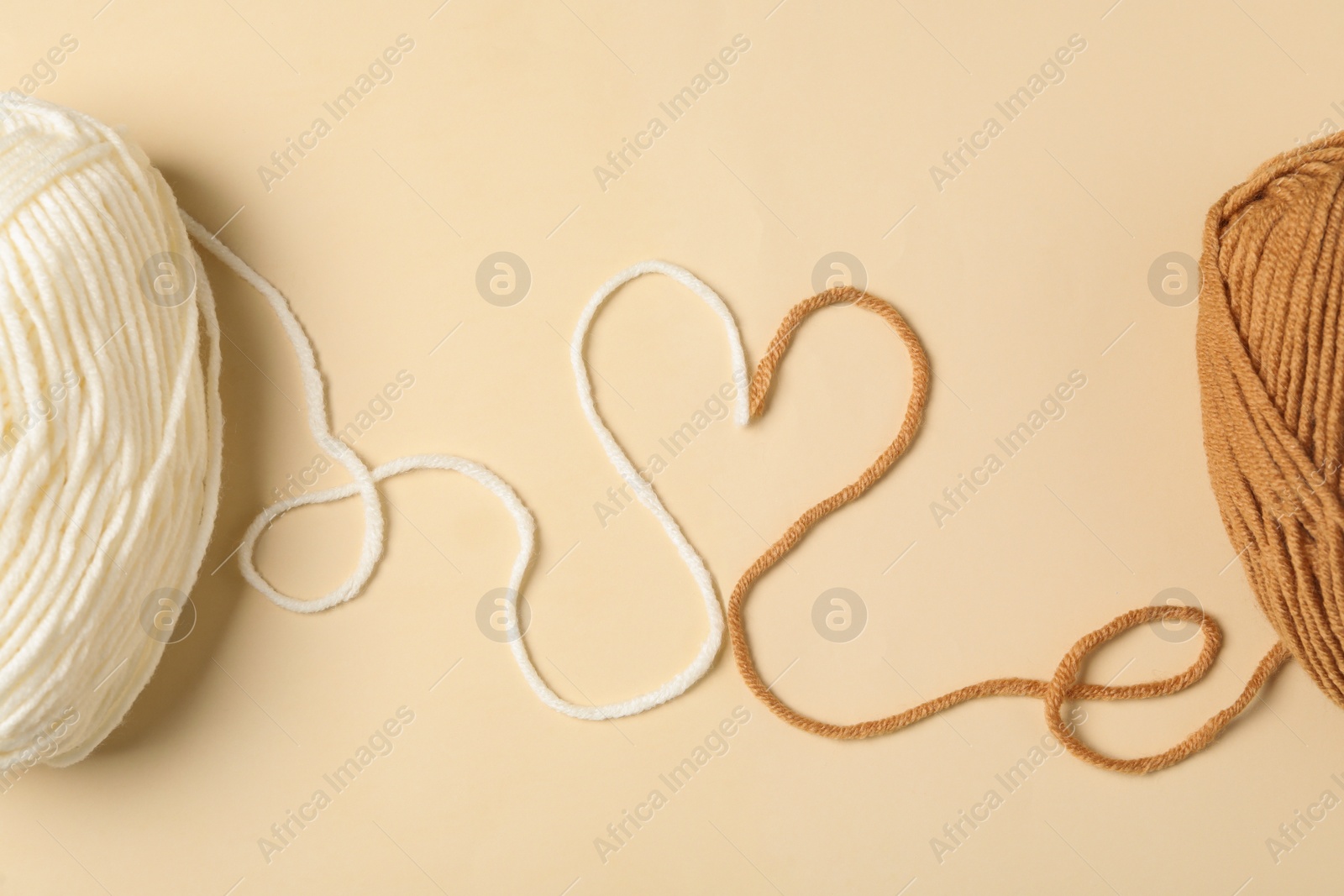 Photo of Heart made with threads and woolen yarns on beige background, flat lay