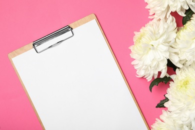 Blank clipboard and chrysanthemum flowers on pink background, flat lay. Teacher's day