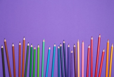 Photo of Colorful pencils on purple background, flat lay. Space for text