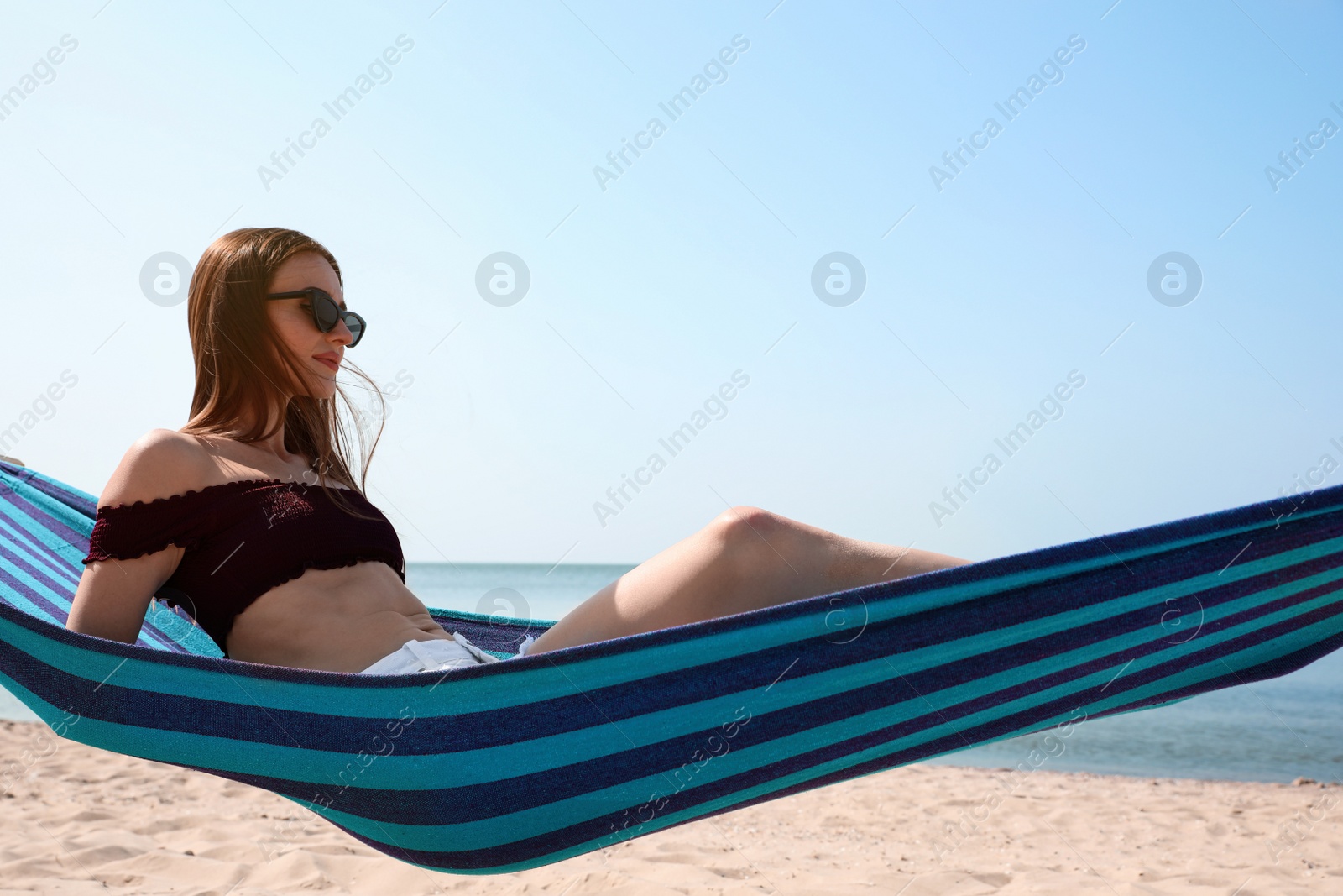 Photo of Young woman relaxing in hammock on beach