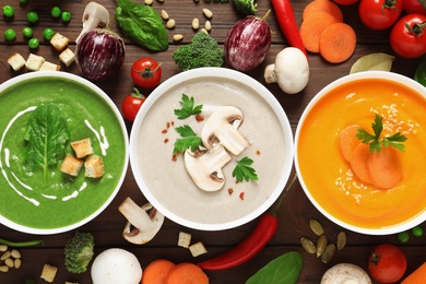 Photo of Various cream soups and ingredients on wooden background, flat lay. Healthy food