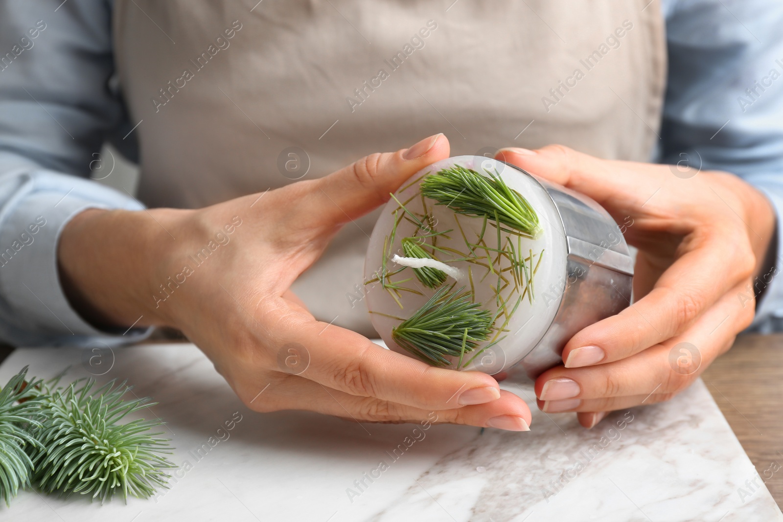 Photo of Woman making conifer candle at table, closeup